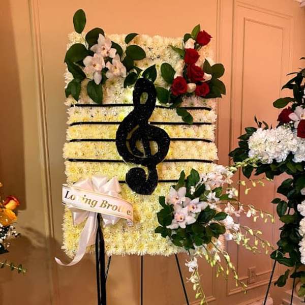 Standing floral tribute with a black treble clef on a white flower panel