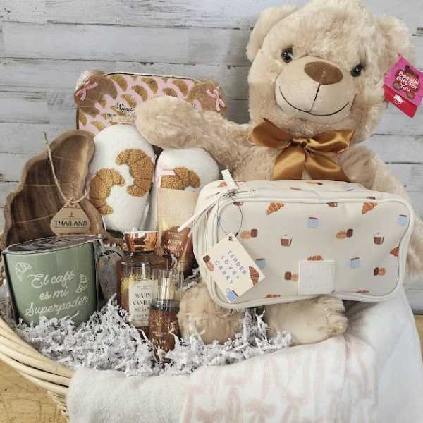 Gift basket with a teddy bear, candles, slippers, and a cosmetic bag
