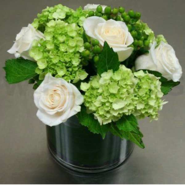 White roses and green hydrangeas in a dark glass vase