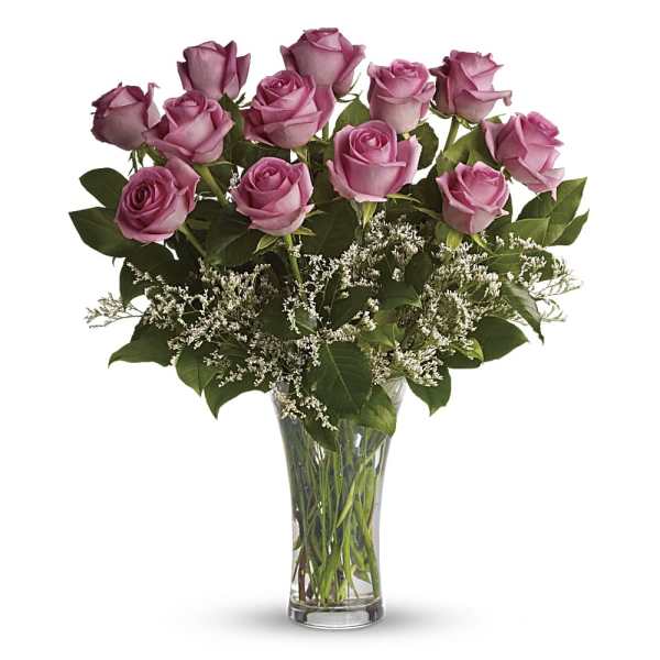 Dozen pink roses with white filler flowers in a clear glass vase