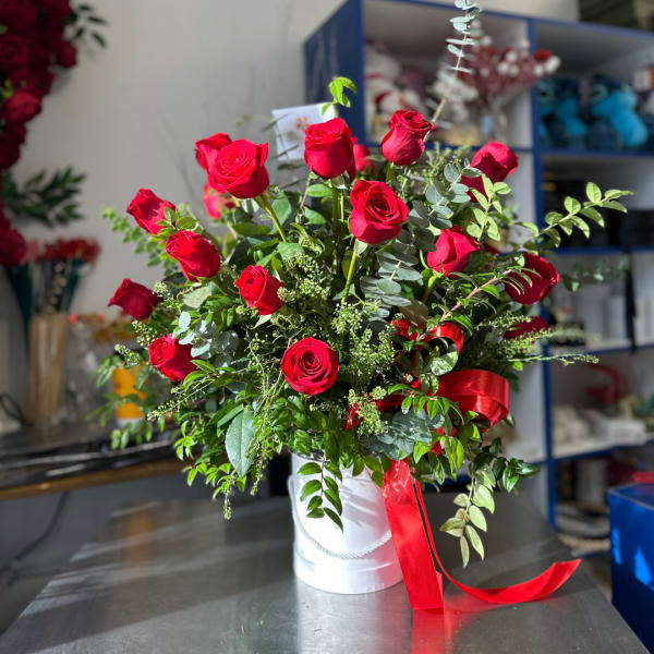 Red roses arranged in a white hatbox with a red ribbon.