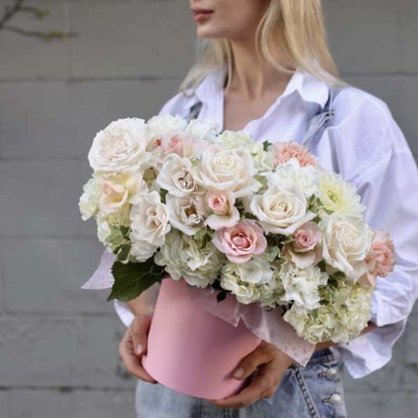 Woman holding a pink box of white and blush roses and hydrangeas