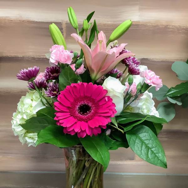 Bouquet of pink lilies, gerbera daisies, and mixed blooms in a glass vase