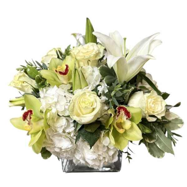 White lilies and pale roses in a square glass vase