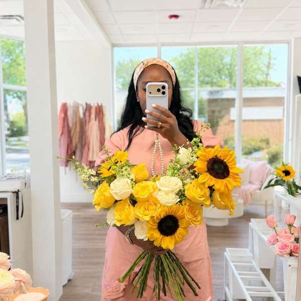 Woman holding a bouquet of yellow sunflowers and cream roses