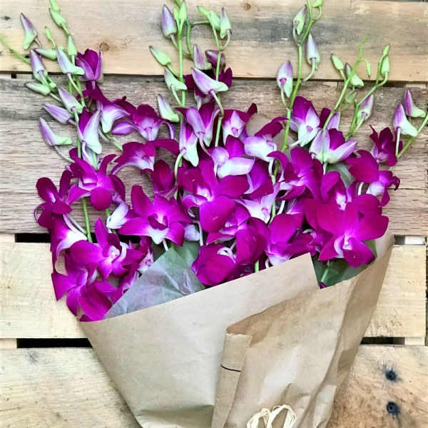 Bouquet of purple orchids wrapped in brown paper