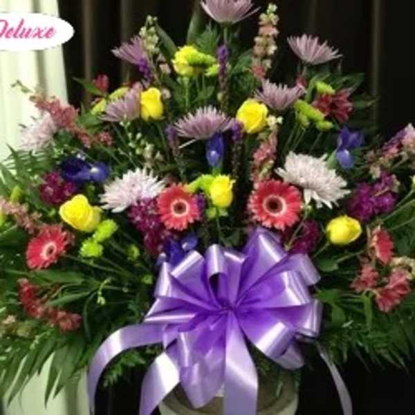 Large mixed flower arrangement with a purple ribbon bow