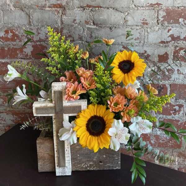 Sunflowers and white lilies arranged with a wooden cross