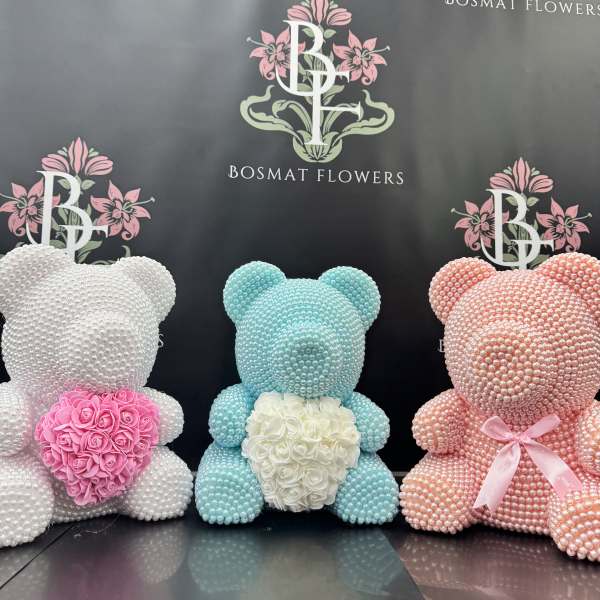 Three pearl-covered teddy bears with floral hearts in pink, white, and blue.