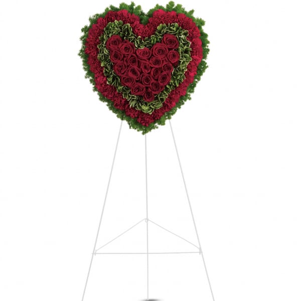 Heart-shaped floral wreath of red roses and carnations on a stand