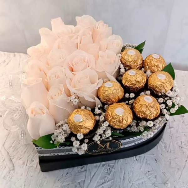 Blush rose arrangement with gold-wrapped chocolates in a black box