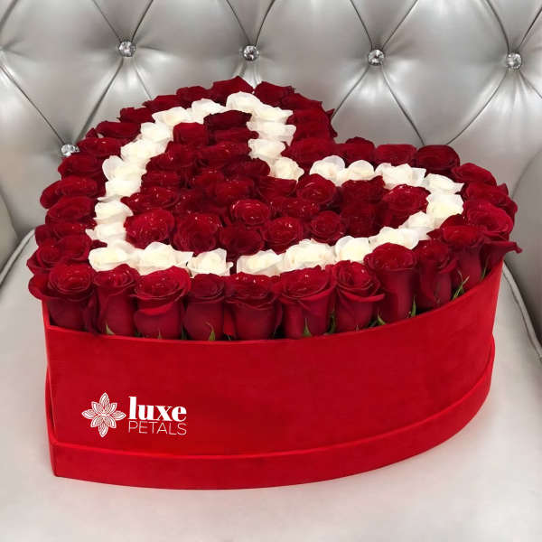 Heart-shaped box of red and white roses on a tufted silver chair
