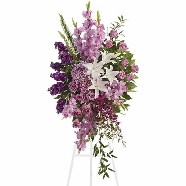Tall lavender and white standing spray with lilies and roses on a white easel