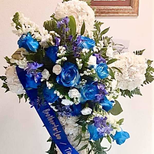 Blue and white funeral spray with roses and hydrangeas on a stand