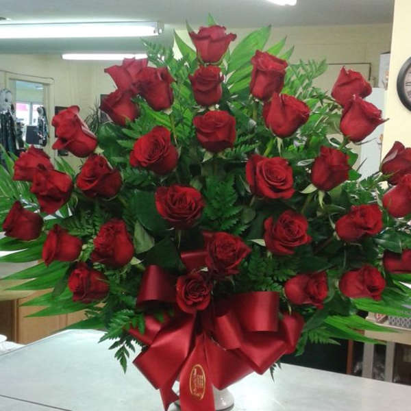 Large bouquet of red roses with a red ribbon in a white vase