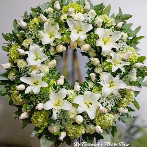 Large standing wreath of white lilies, roses, and hydrangeas on an easel