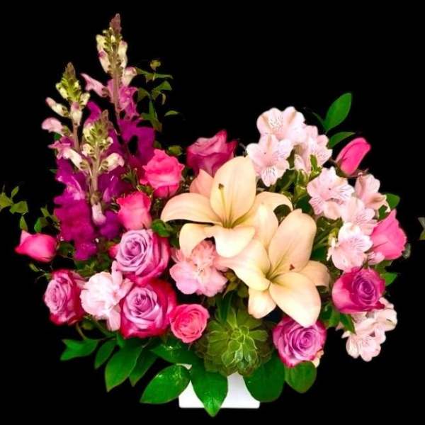 Pink and cream floral arrangement with roses, lilies, and alstroemeria in a white container