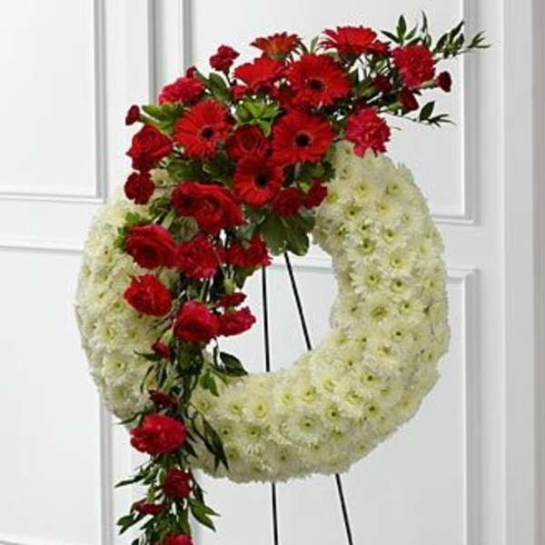 Red and white floral funeral wreath on a stand
