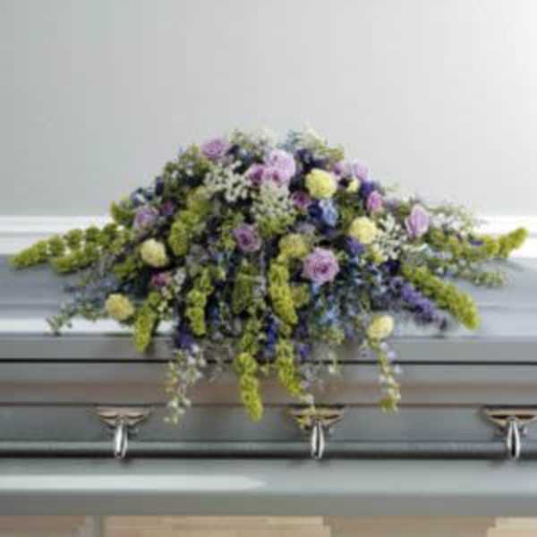 Pastel floral casket spray with purple, yellow, and white blooms