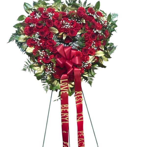 Heart-shaped red rose standing spray with ribbons on an easel