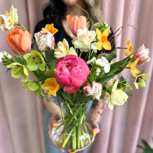 Mixed bouquet of tulips and daffodils in a clear glass vase