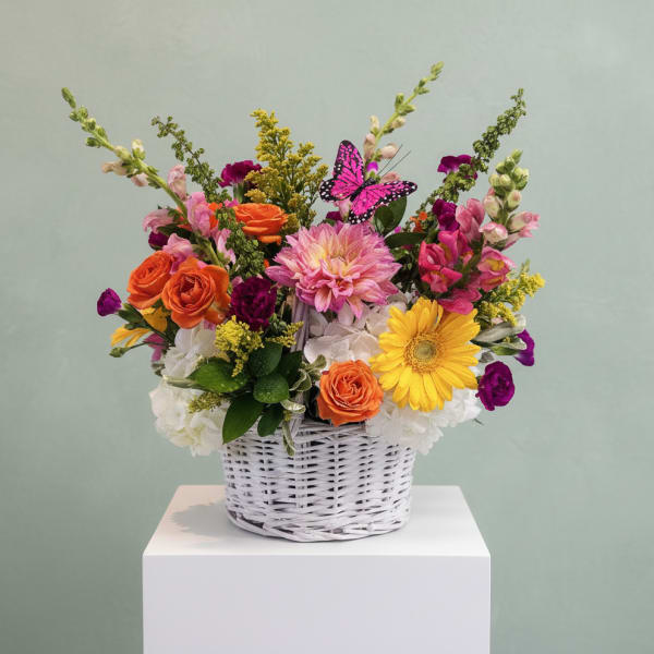 Colorful mixed flower arrangement in a white wicker basket