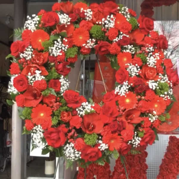 Large red floral wreath on a stand with hanging rose garlands