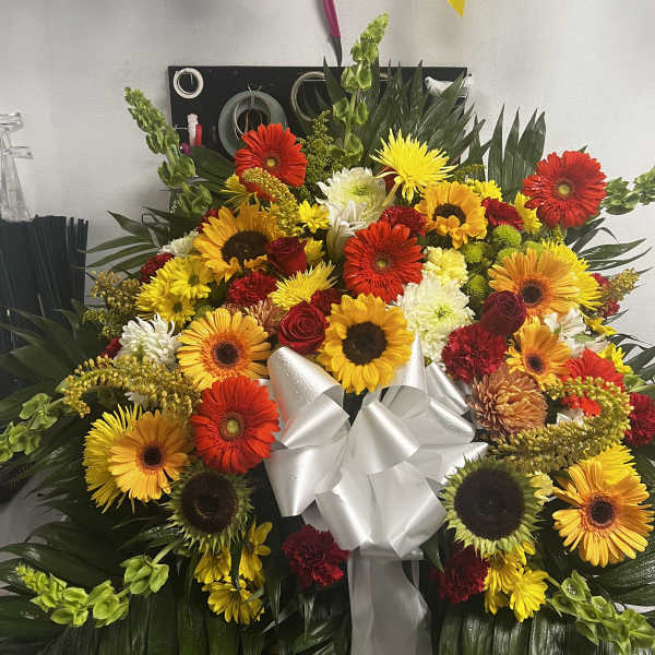 Large mixed flower arrangement with a white ribbon bow