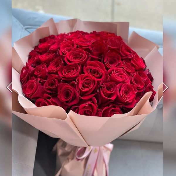 Large bouquet of red roses wrapped in pale pink paper