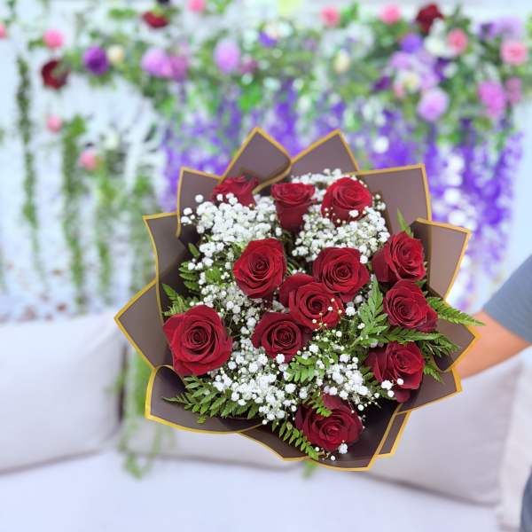 Bouquet of red roses with white filler flowers and brown wrap