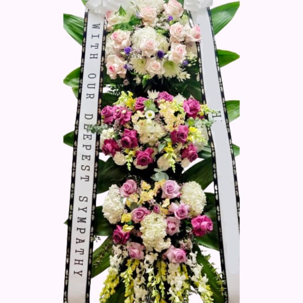 Tall sympathy standing spray with pink and white roses and ribbons
