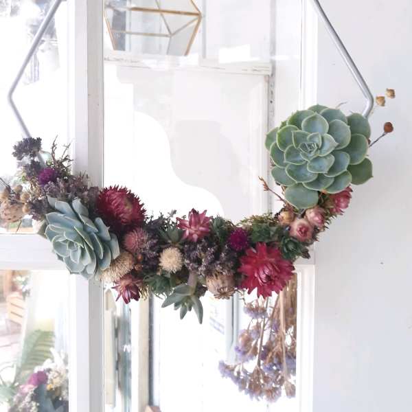 Succulent wreath with pink and purple dried flowers on a metal frame