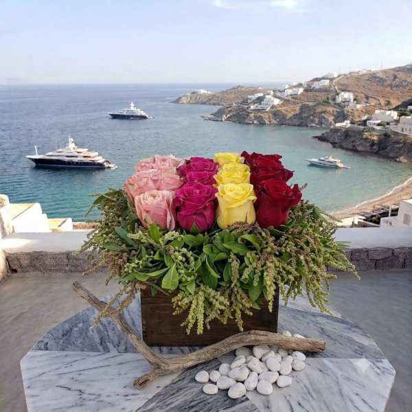 Mixed roses in a wooden box with driftwood and white stones