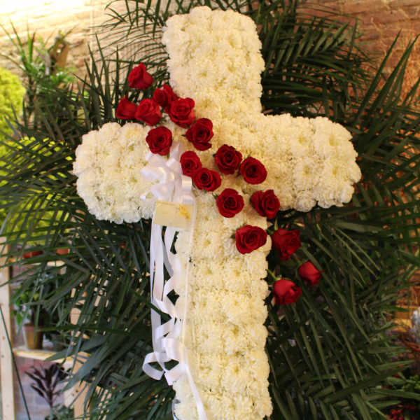 White floral cross with red roses and a white ribbon