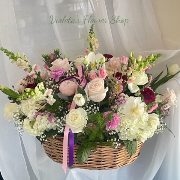 Basket arrangement of pink and white flowers with ribbon accents