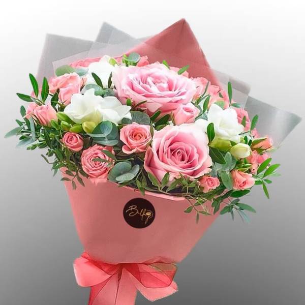 Pink and white rose bouquet wrapped in pink paper with a ribbon