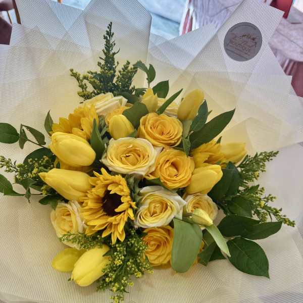 Yellow bouquet with roses and tulips wrapped in white paper