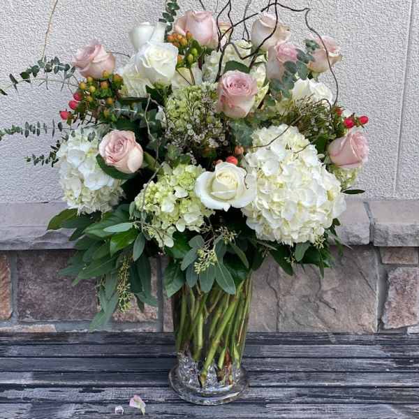 Bouquet of pale pink roses and white hydrangeas in a clear glass vase