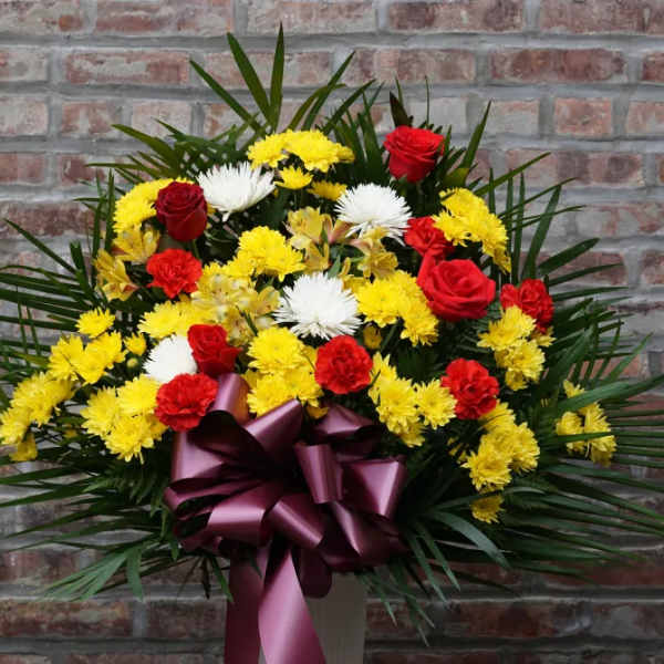 Red roses and yellow-white chrysanthemums in a vase with a purple ribbon