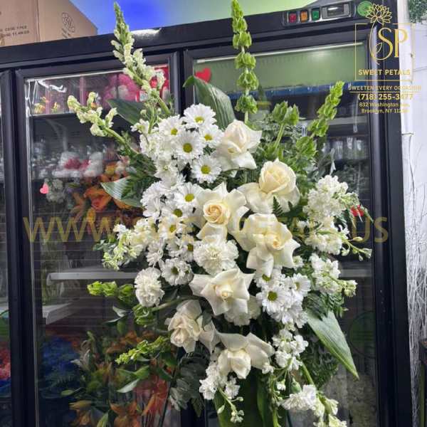 Tall white floral standing arrangement with roses, daisies, and calla lilies