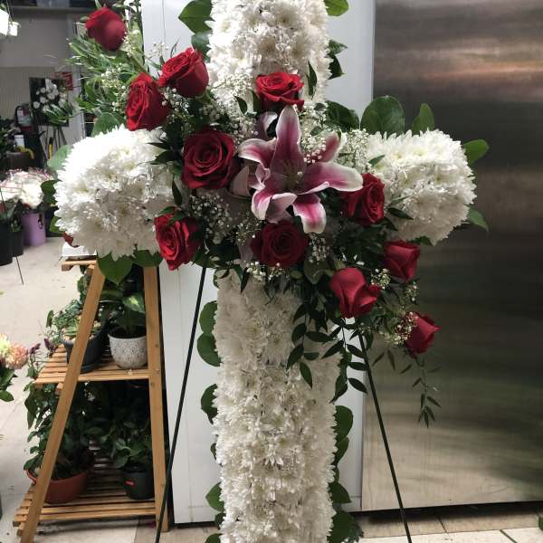 Cross-shaped floral spray with white chrysanthemums, red roses, and a pink lily
