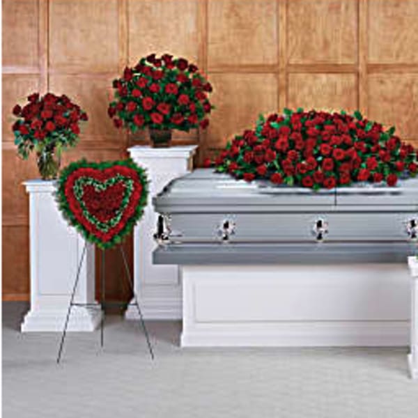 Casket surrounded by red rose funeral sprays and a heart wreath