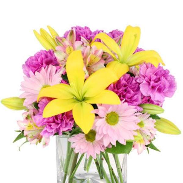 Pink daisies, yellow lilies, and purple carnations in a clear glass vase
