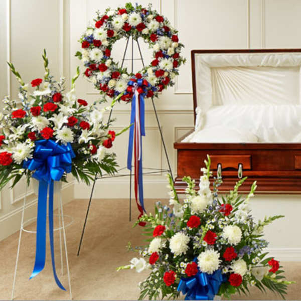Casket surrounded by red, white, and blue funeral flower sprays