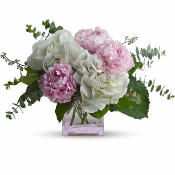 Pink and white peonies in a square glass vase
