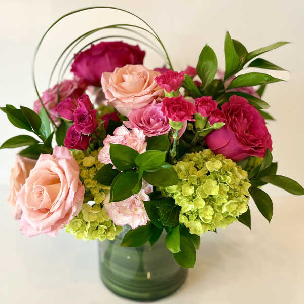 Pink and peach roses with green hydrangeas in a glass vase