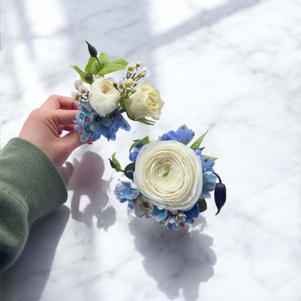 Two small floral wedding pieces with white blooms and blue accents