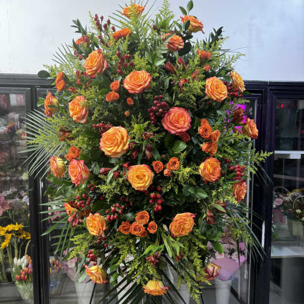 Large standing spray of orange roses with red berries and greenery