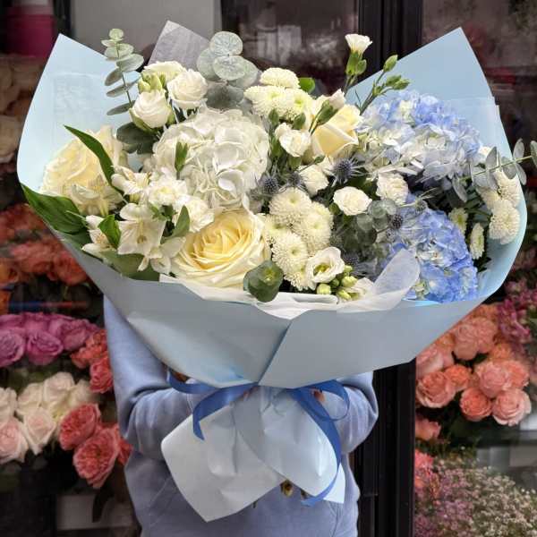 Large bouquet of white and pale blue flowers wrapped in light blue paper