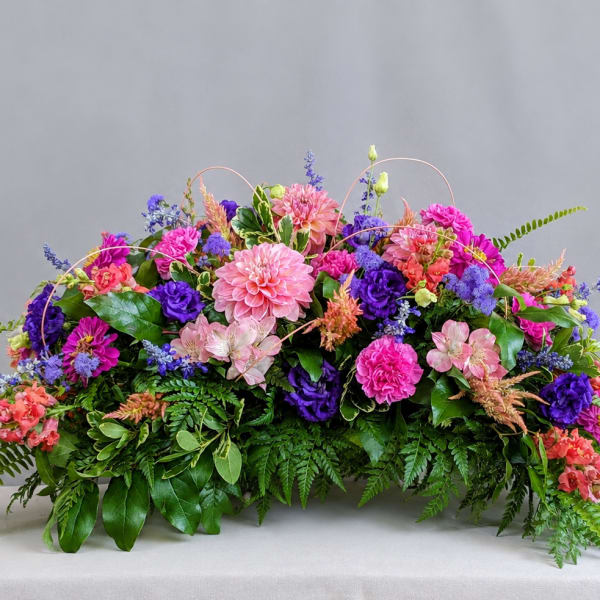 Low floral centerpiece with pink, purple, and coral blooms
